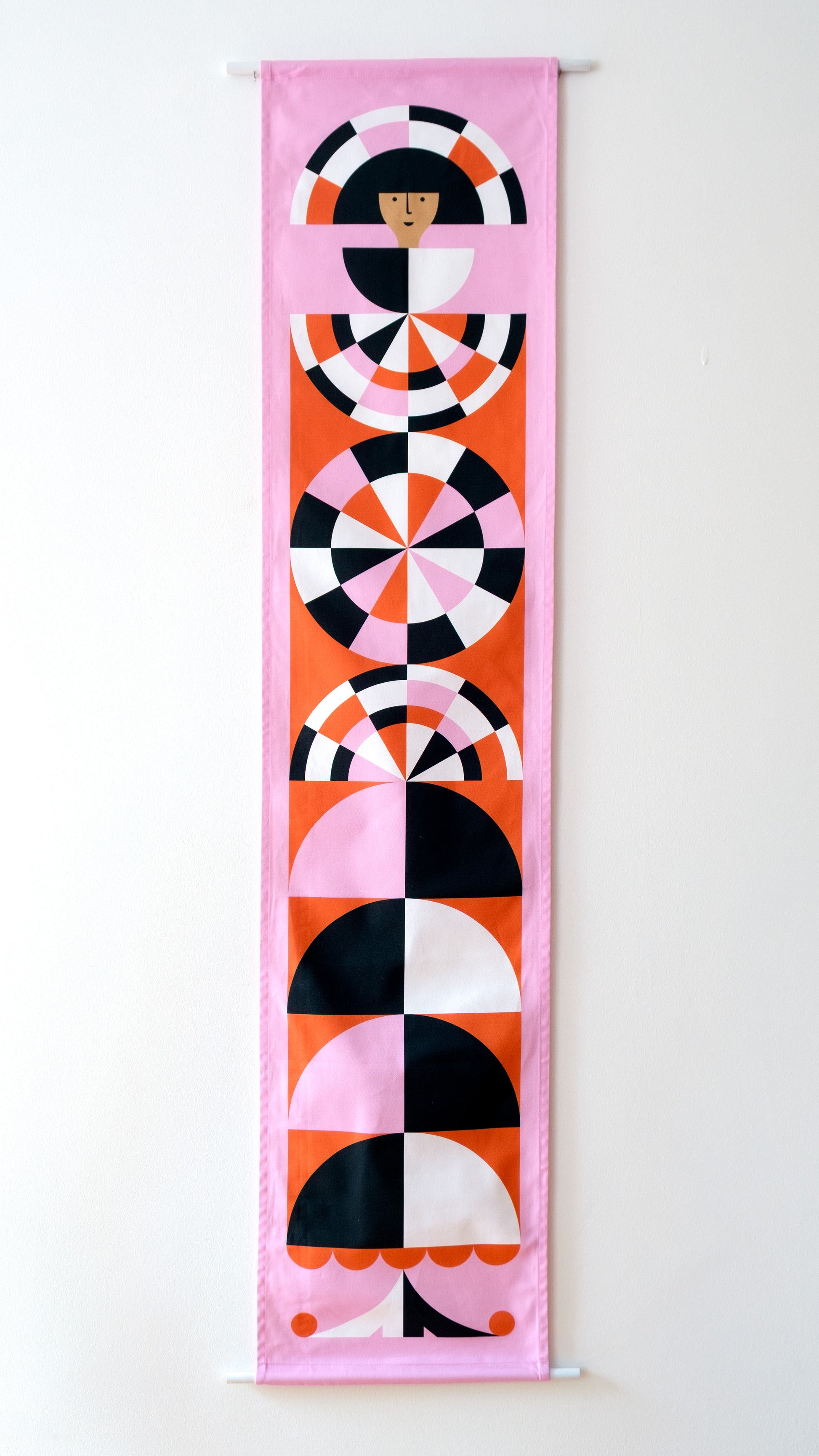 A fabric banner featuring a red and pink geometric figure with black and white accents. 