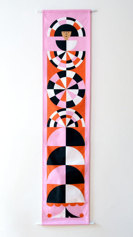 A fabric banner featuring a red and pink geometric figure with black and white accents. 