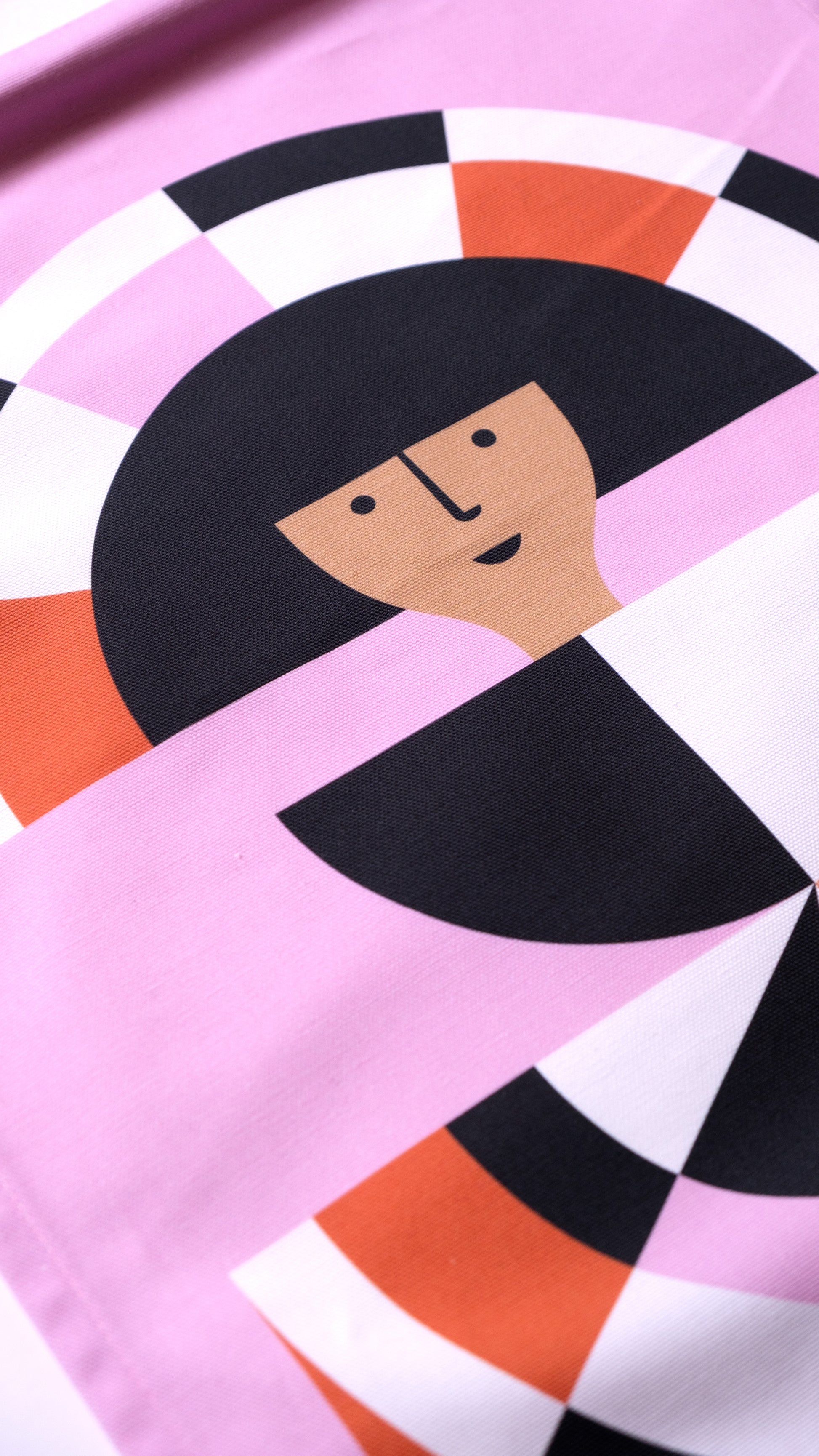 A close up detail of a fabric banner featuring a red and pink geometric figure with black and white accents. 
