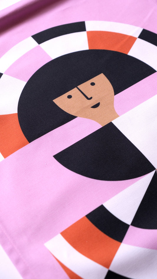 A close up detail of a fabric banner featuring a red and pink geometric figure with black and white accents. 