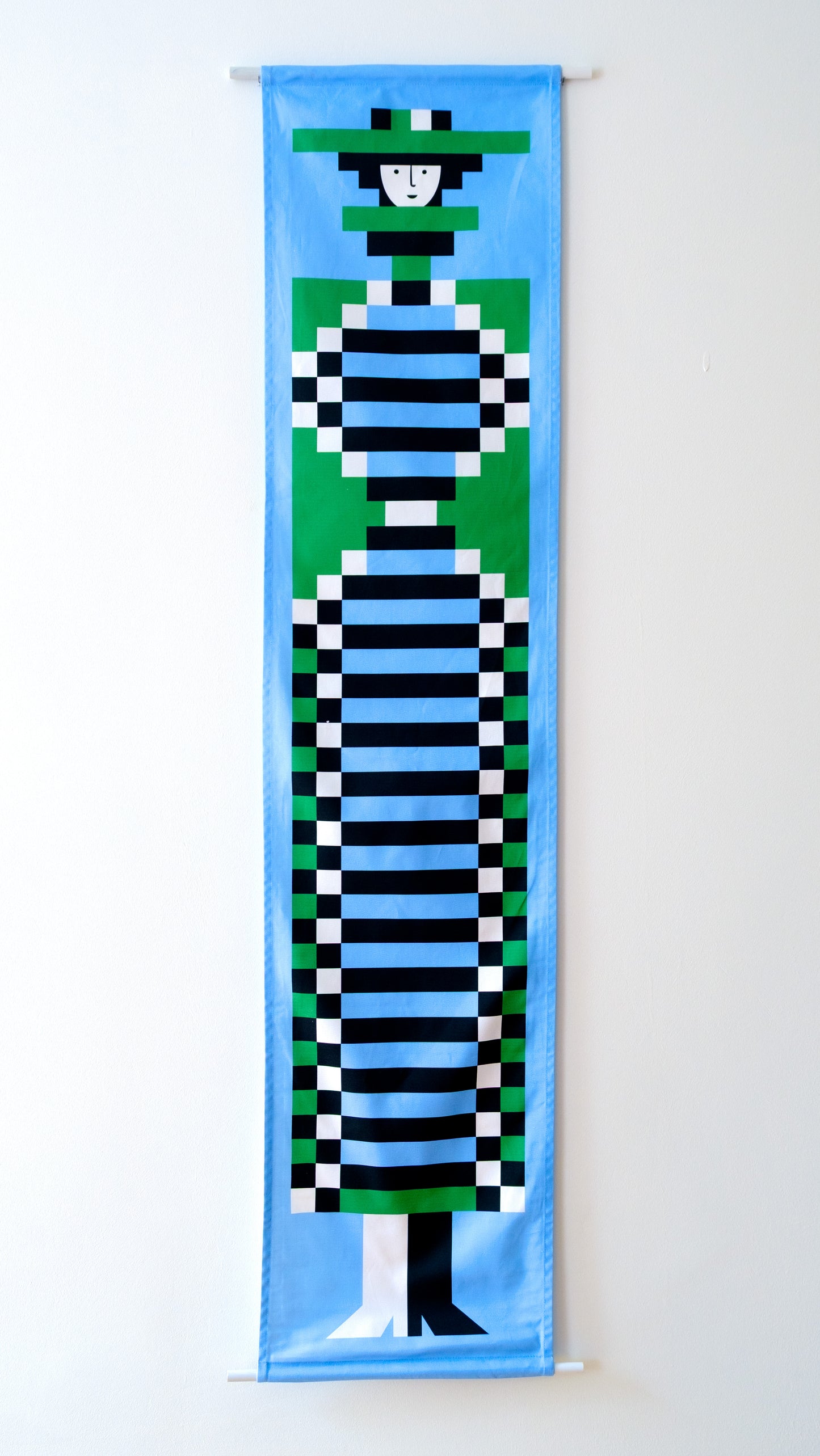 A fabric banner featuring a blue and green geometric figure with black and white accents. 
