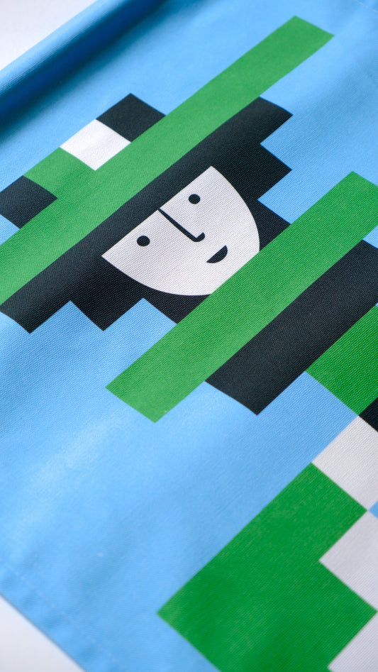 A close up detail of a fabric banner featuring a green and blue geometric figure with black and white accents.