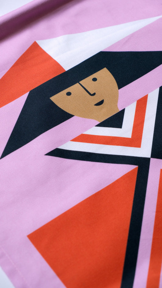 A detail shot of a  fabric banner featuring a red and pink geometric figure with black and white accents. 