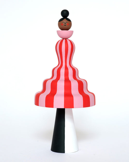 A colourful sculpture with a pink and red stripey body with white and black legs on a plain white background.