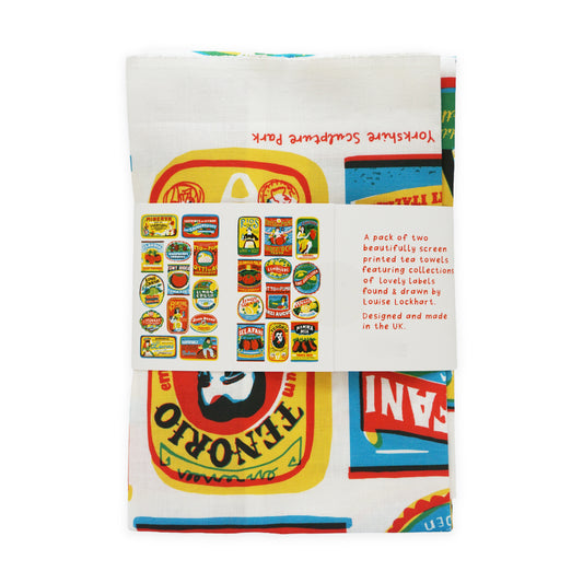 A pack of two vibrant tea towels featuring colourful screen-printed designs inspired by vintage labels. The towels are neatly folded and wrapped, showcasing a label with illustrations by Louise Lockhart, designed and made in the UK.