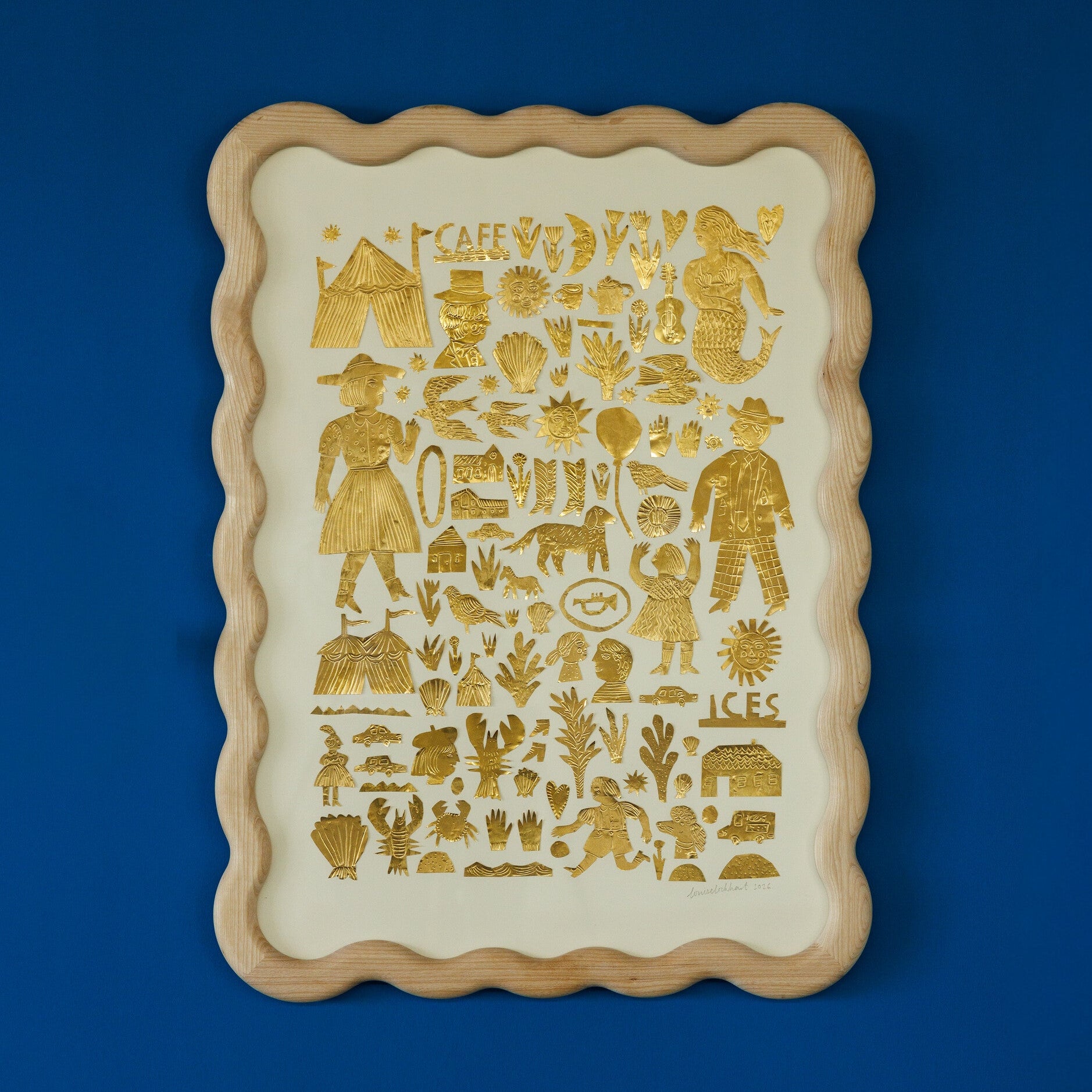 A decorative tray featuring a variety of gold illustrations on a cream background. The designs include people, animals, plants, and various symbols, all arranged in a grid pattern. The tray has a scalloped wooden frame and is set against a blue wall.