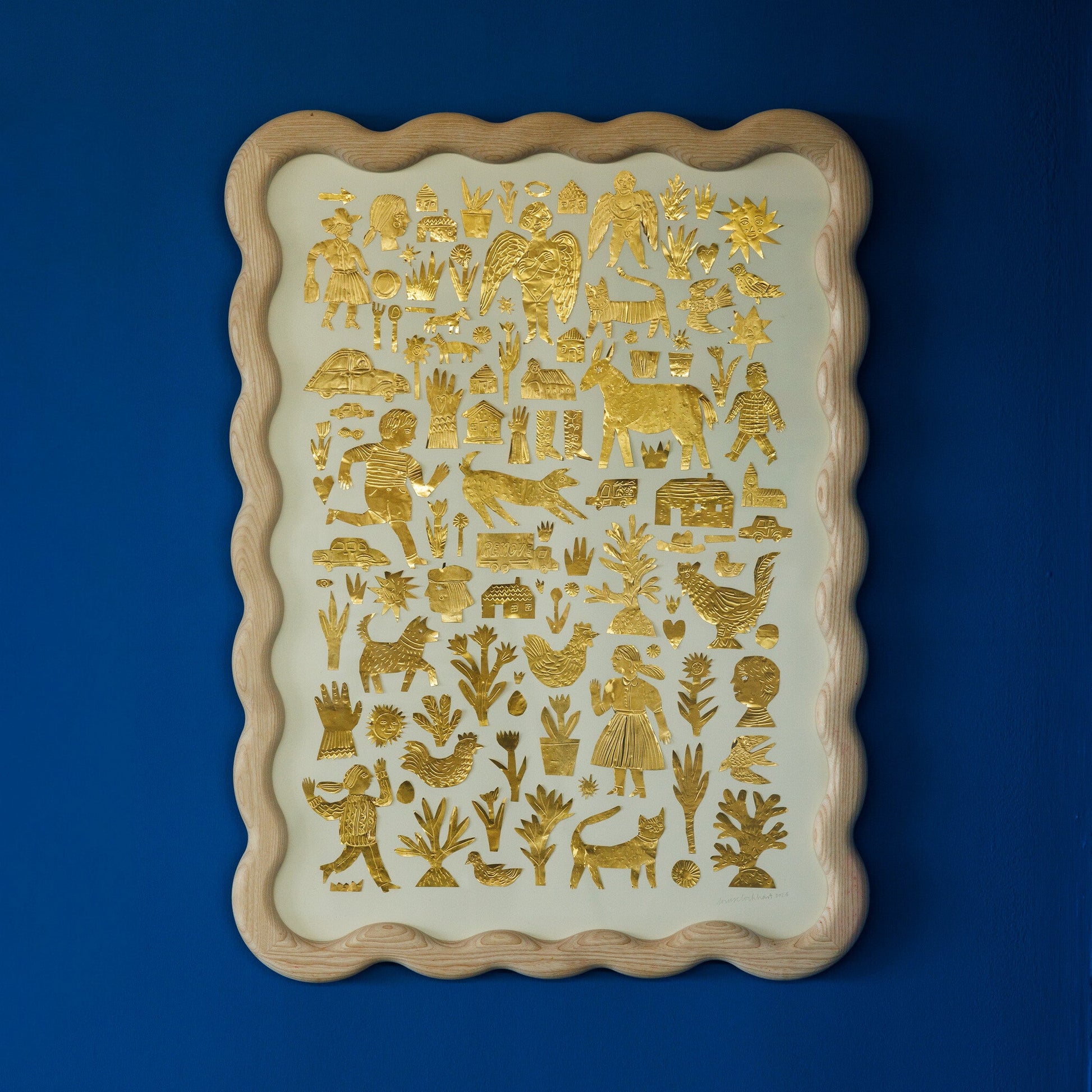 A decorative wall art piece featuring intricate gold foil illustrations on a cream background. The designs include various animals, plants, and human figures, all framed in a scalloped wooden border, set against a deep blue wall.