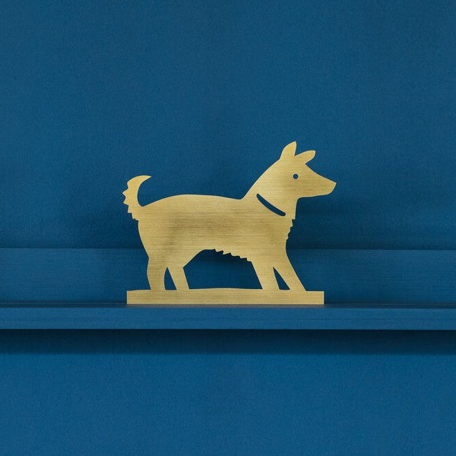Gold dog figure on a blue shelf against a blue background
