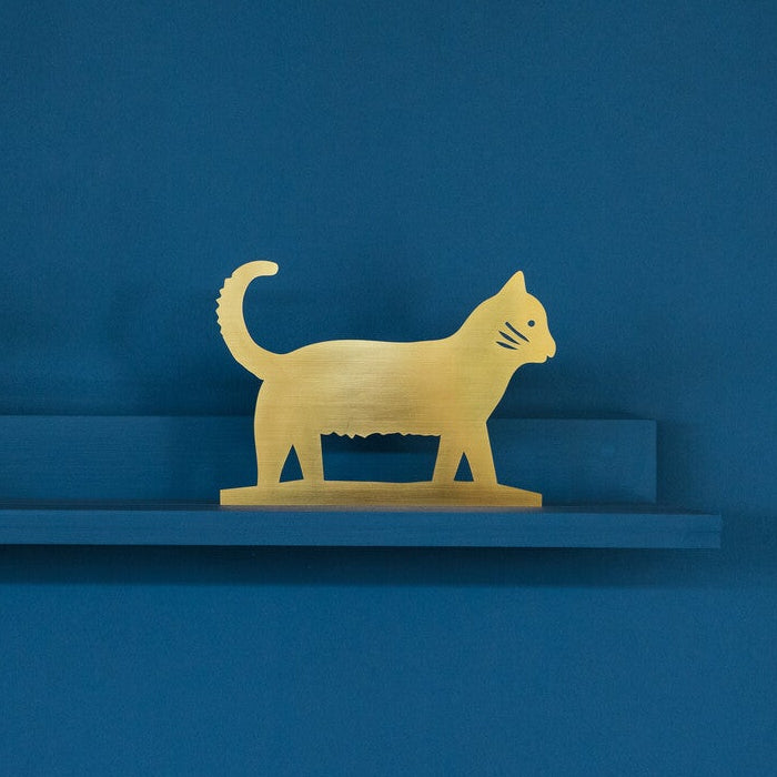 Gold cat figurine on a blue shelf against a blue background