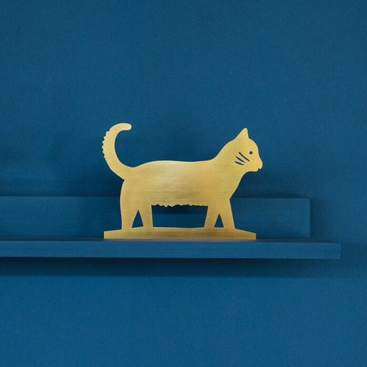 Gold cat figurine on a blue shelf against a blue background