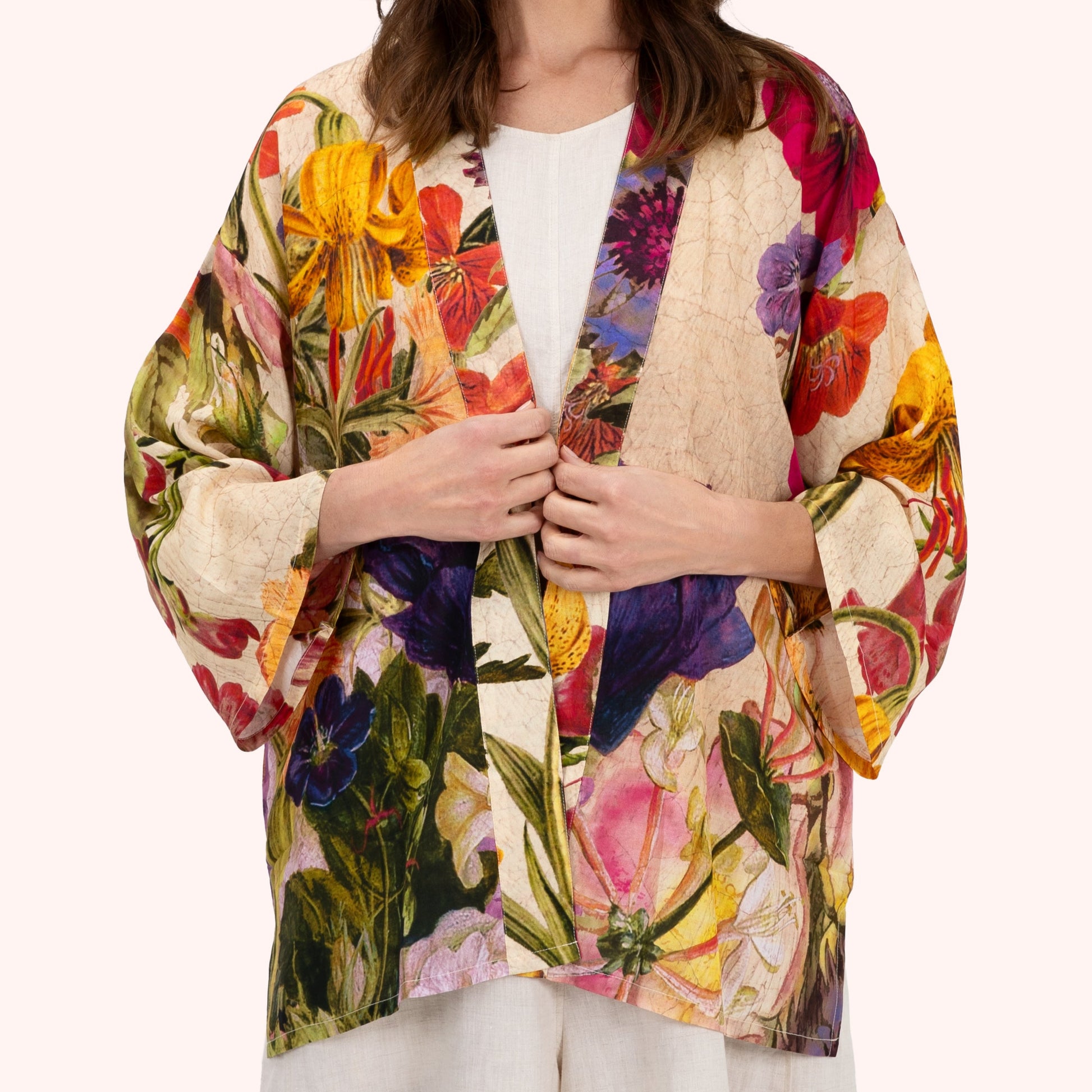 Woman wearing a colorful floral kimono-style jacket on a white background