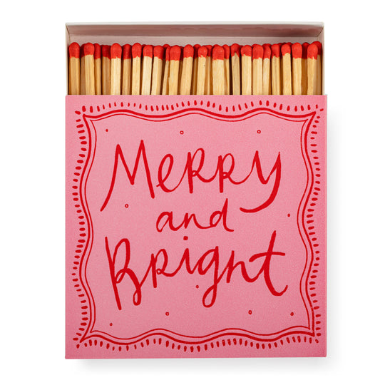 Pink and red matchbox with 'Merry and Bright' text on a white background