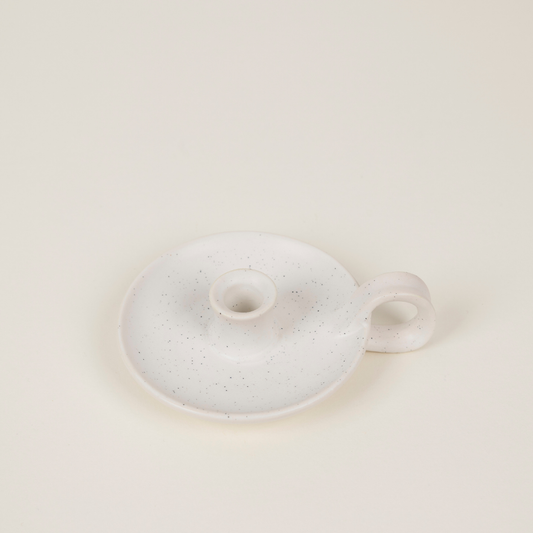 Speckled ceramic candle holder with a small handle on a light beige background