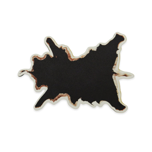 Abstract black shape with irregular, jagged edges and a brownish outline, resembling a cow hide. The background is plain white, highlighting the contrast and unique form of the shape.