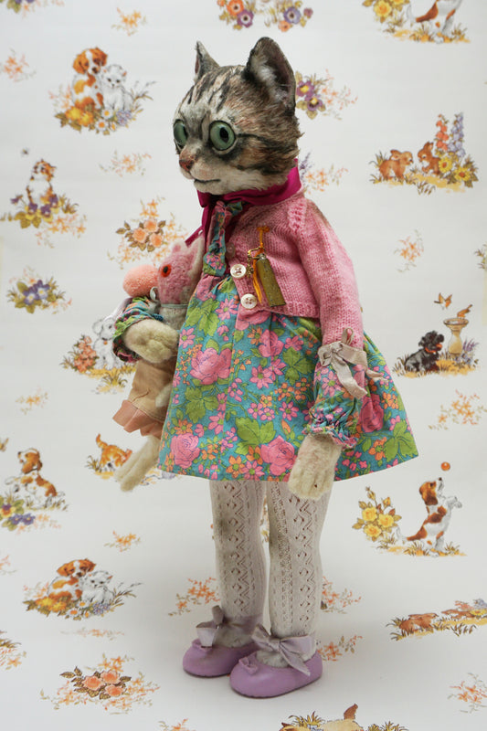 A whimsical cat doll dressed in a floral dress, pink cardigan, and purple shoes holds two smaller plush toys. The background features playful animal illustrations, adding a charming, vintage feel to the scene.