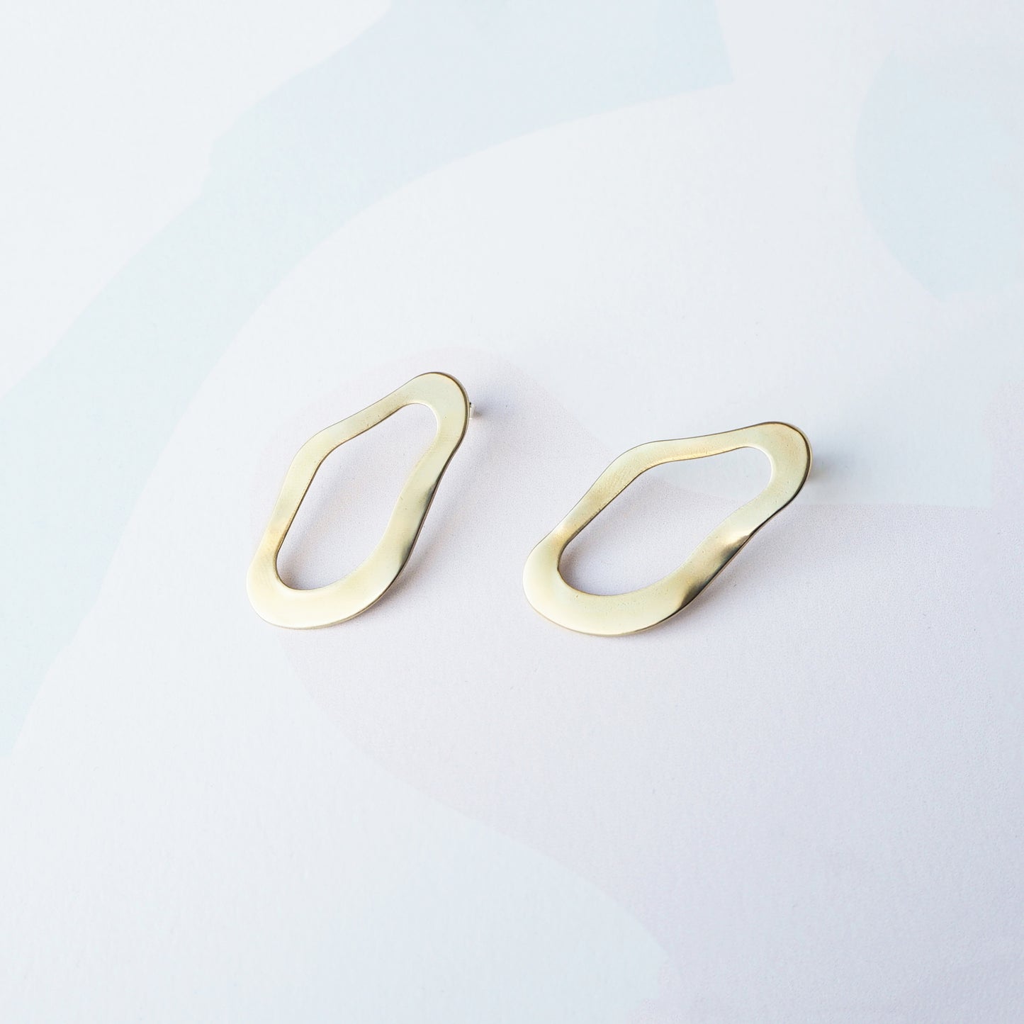 Gold earrings on a light gray background