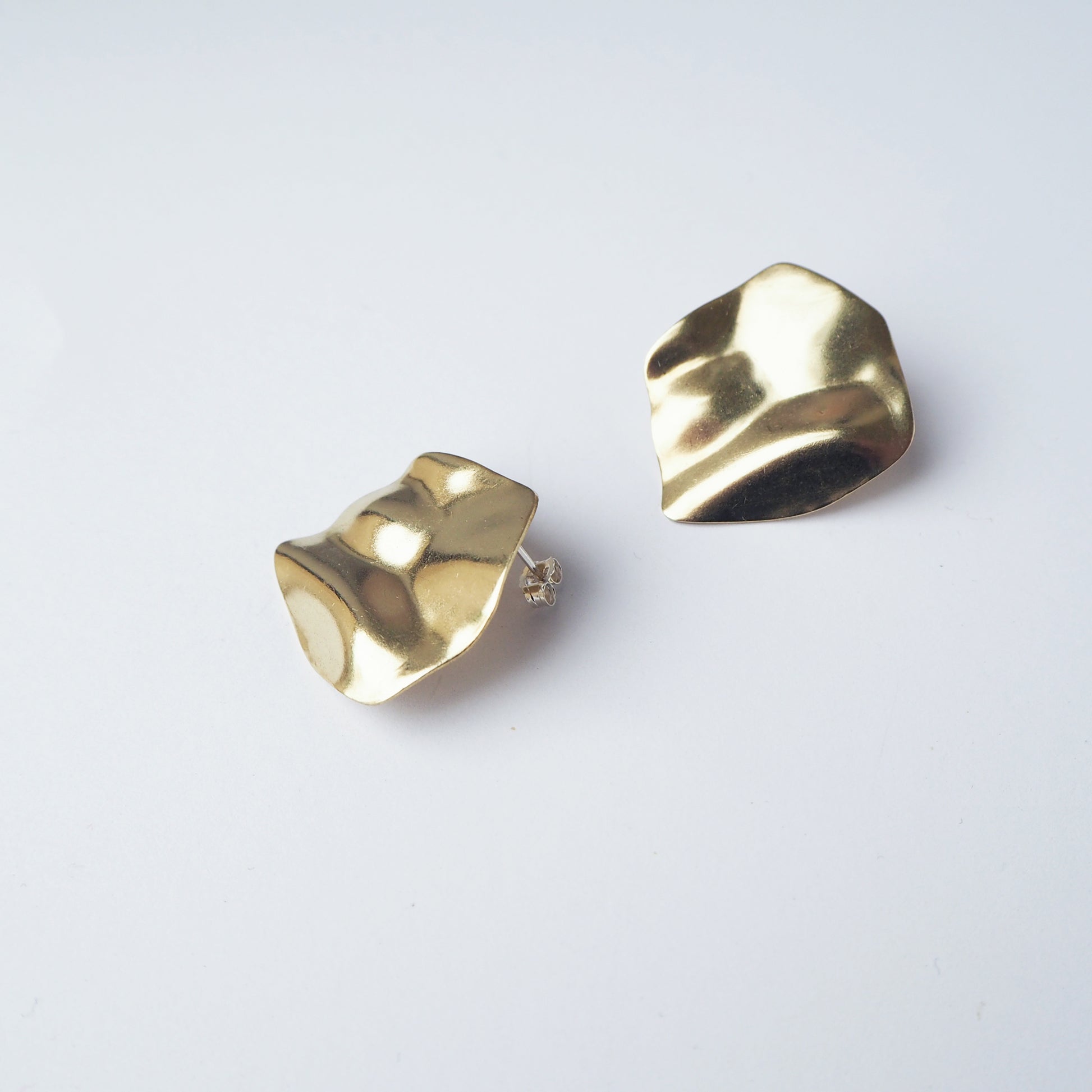 Round gold earrings on a light grey background