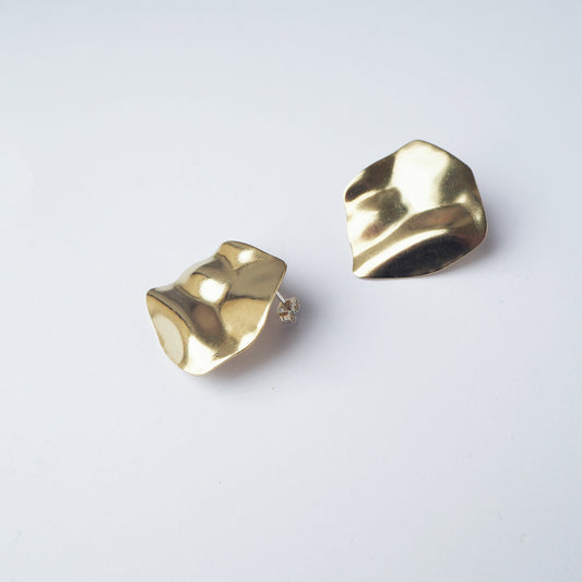 Round gold earrings on a light grey background