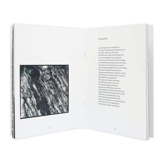 Open book with a black and white photograph on the left page and text on the right page.