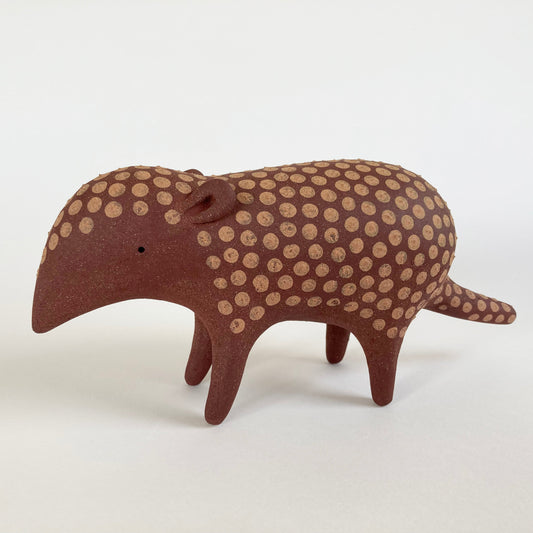 Stylized ceramic armadillo with brown and beige pattern on a white background