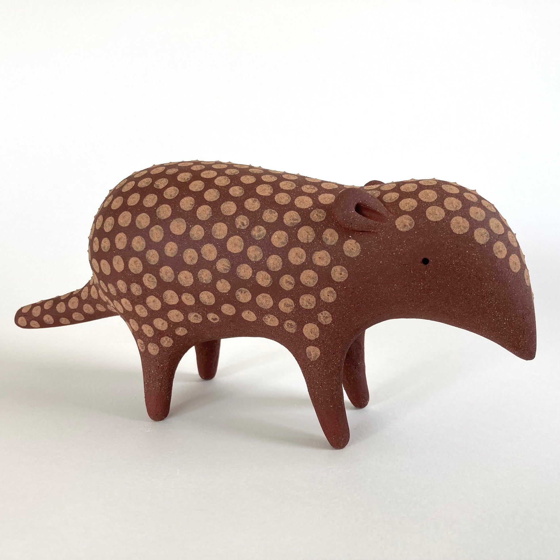 Stylized ceramic armadillo with brown and beige pattern on a white background