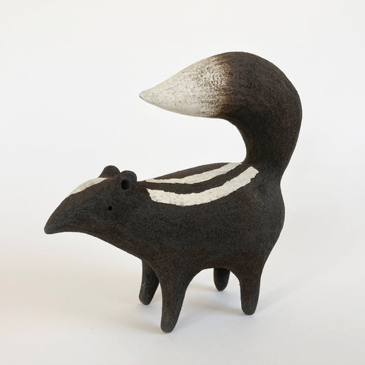 Ceramic sculpture of a skunk on a white background