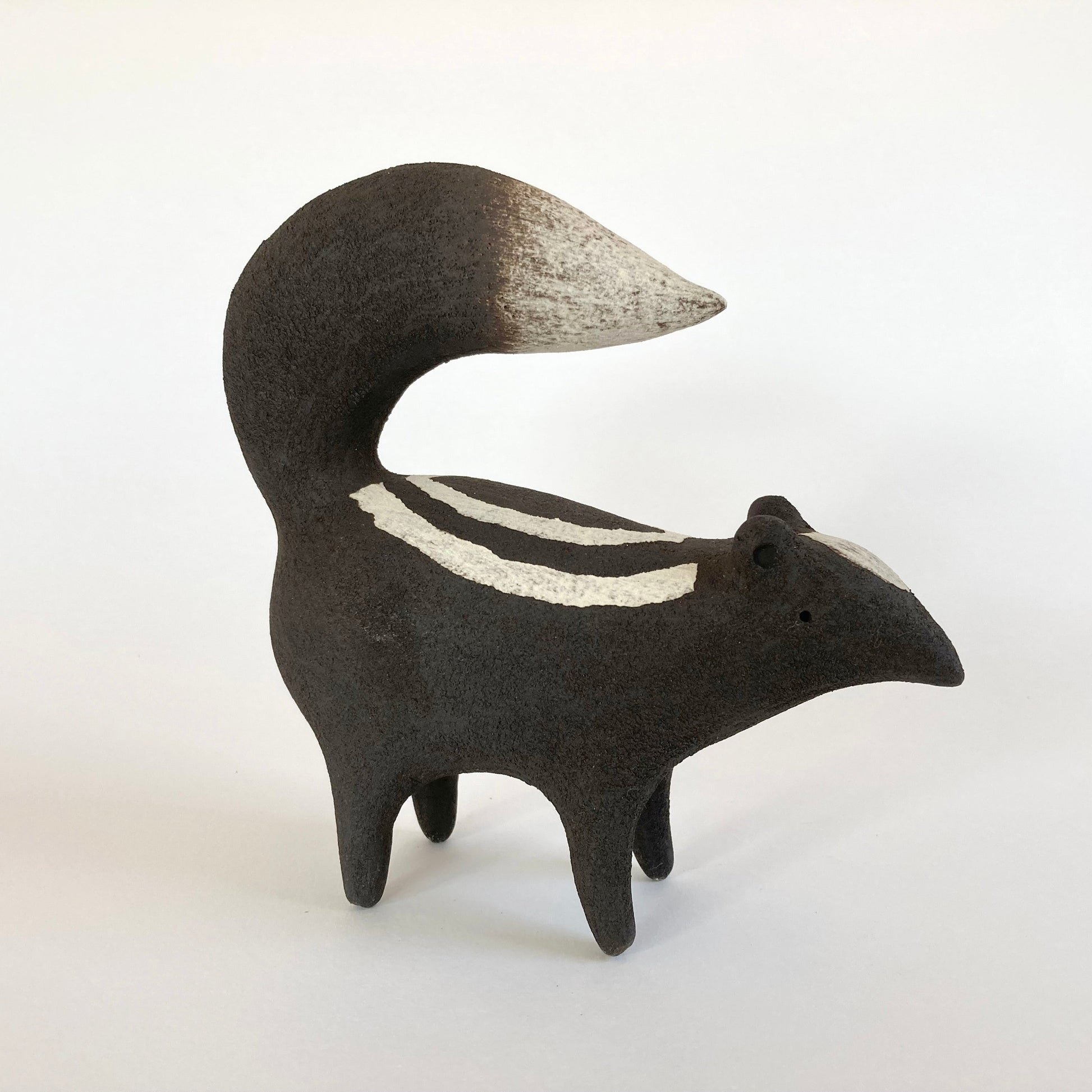 Stylized ceramic animal figure with a striped pattern on a white background