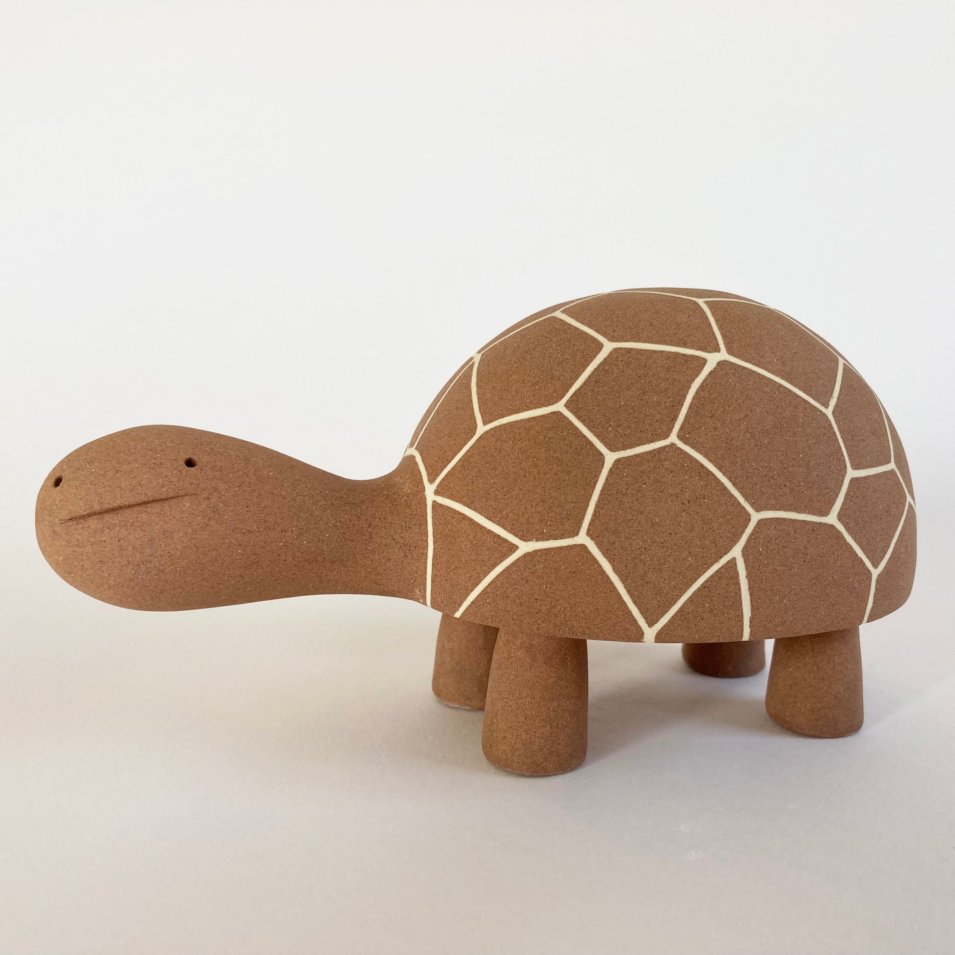 Ceramic tortoise with a brown shell on a white background
