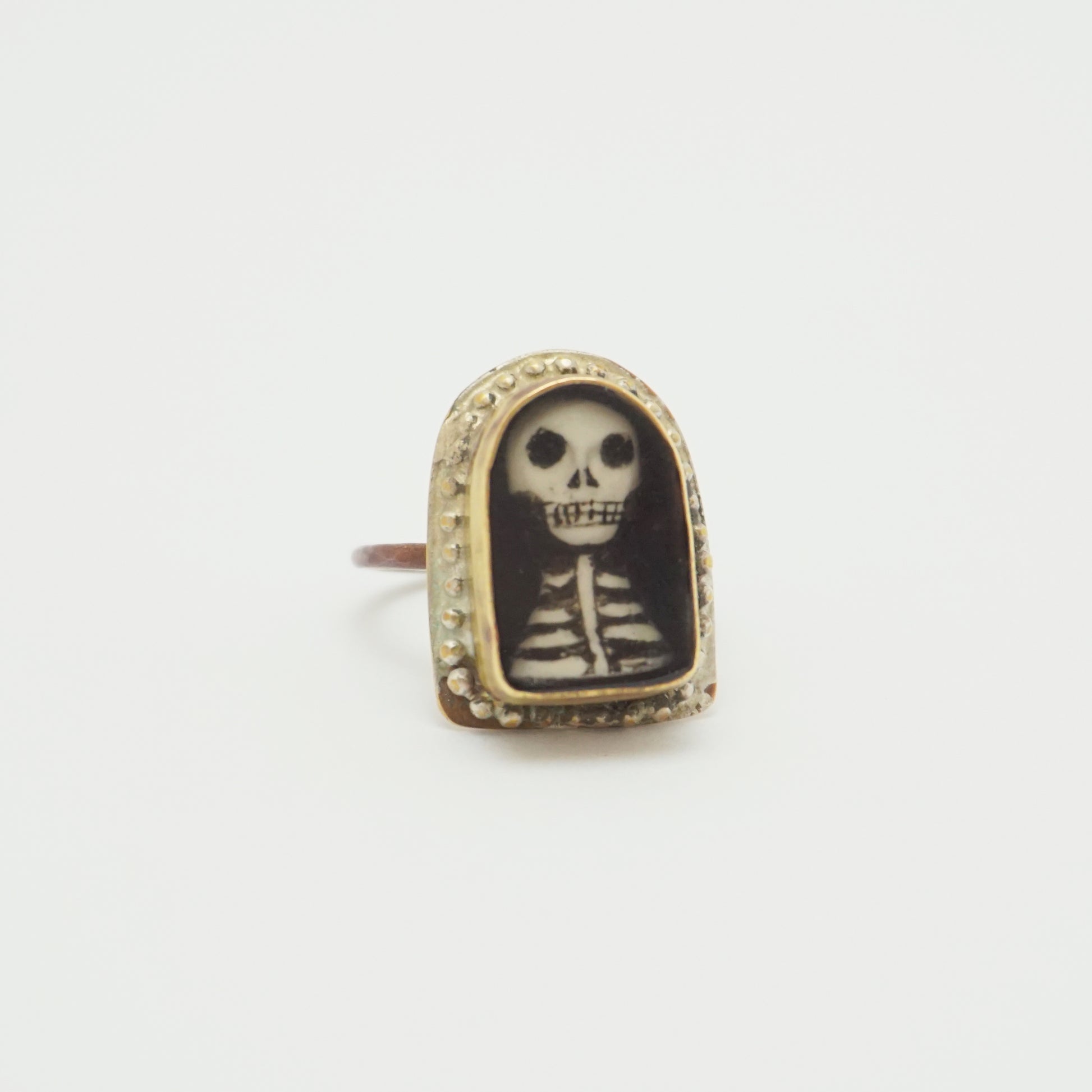 Ring with a hand painted skeleton design in a gold bezel on a white background