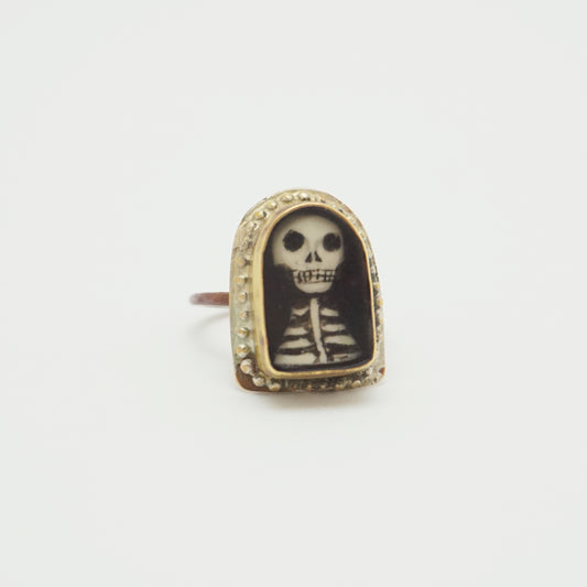 Ring with a hand painted skeleton design in a gold bezel on a white background