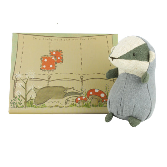 Stuffed badger toy with a card box featuring a forest design on a white background