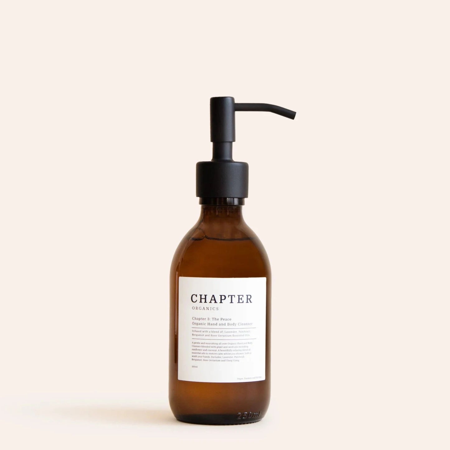 A brown glass pump bottle with a black pump lid. The label features minimalist text, indicating the product name "The Peace" and a brief description. The background is a soft, neutral colour, enhancing the bottle's elegant design.