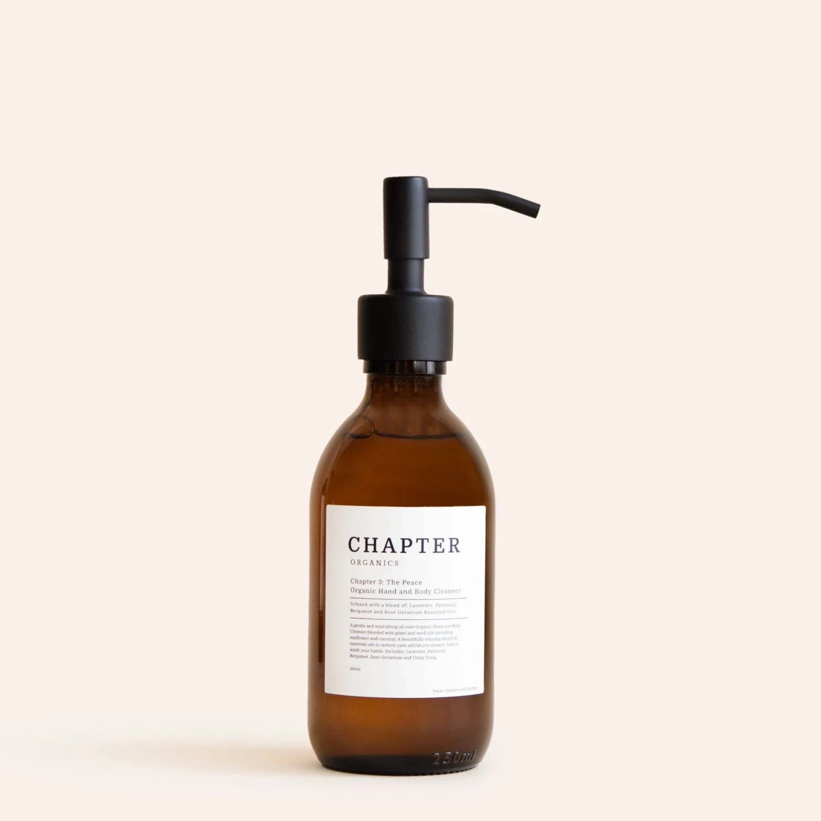 A brown glass pump bottle with a black pump lid. The label features minimalist text, indicating the product name "The Peace" and a brief description. The background is a soft, neutral colour, enhancing the bottle's elegant design.