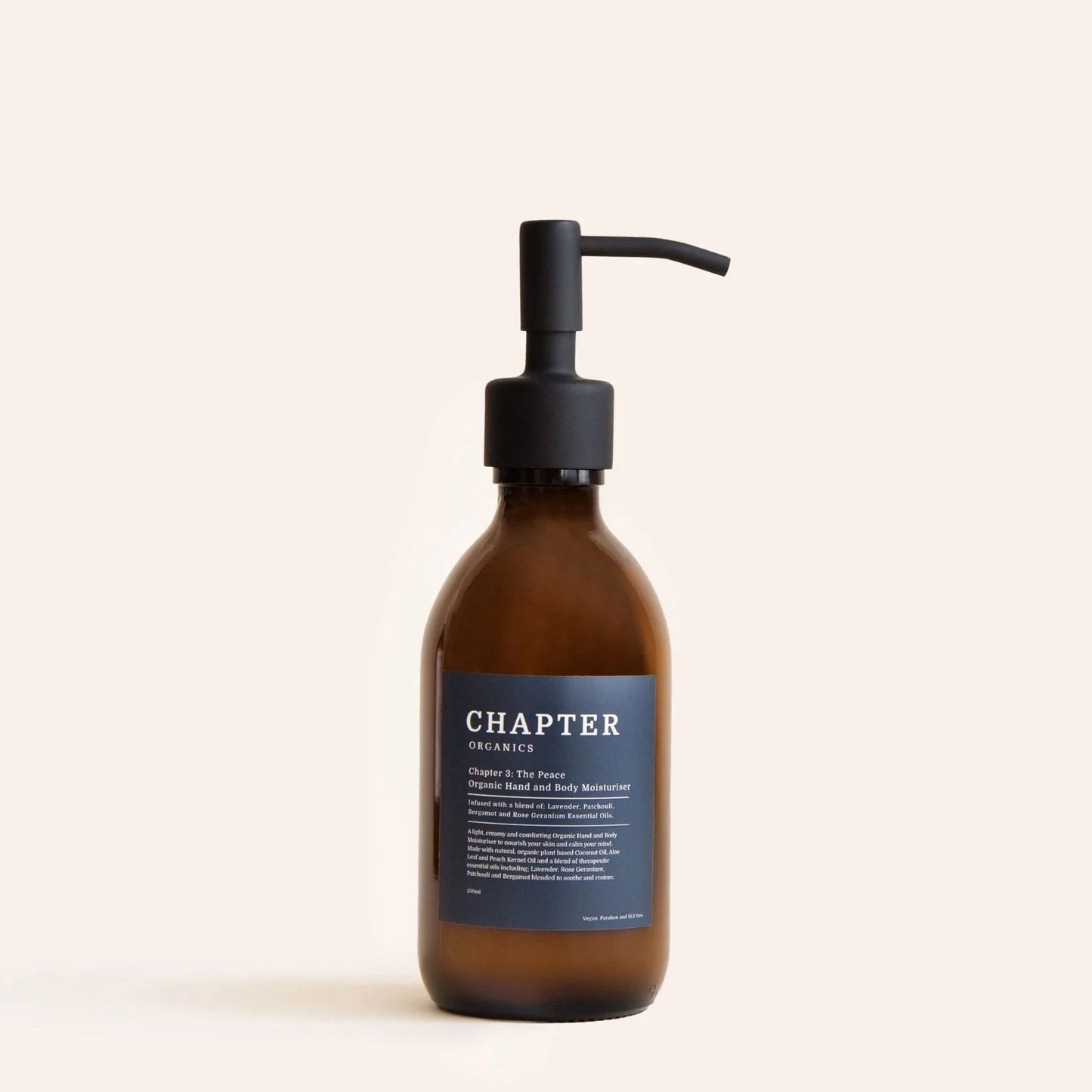 A brown glass bottle with a black pump dispenser, labelled "CHAPTER ORGANICS" in white text. The label features a description of the product and its benefits, set against a light beige background. The overall aesthetic is minimalist and elegant.