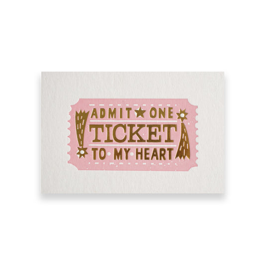 A pink ticket design featuring the text "Admit One Ticket to My Heart" in bold, decorative lettering. The ticket has a vintage style with stars and decorative elements, set against a textured white background.