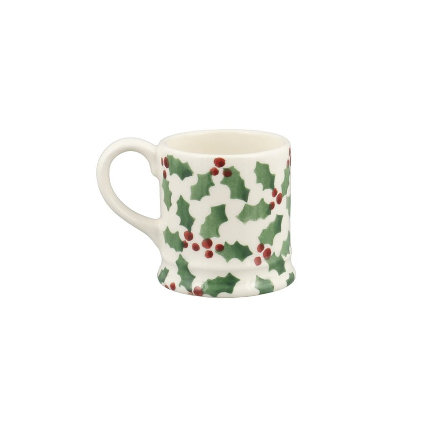 A small white ceramic mug decorated with a green holly and red berry pattern, shown against a plain white background.