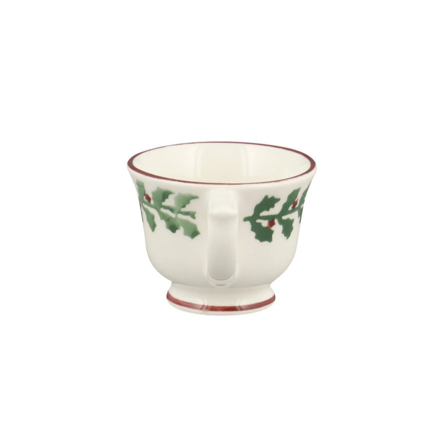 White ceramic cup with holly design on a white background