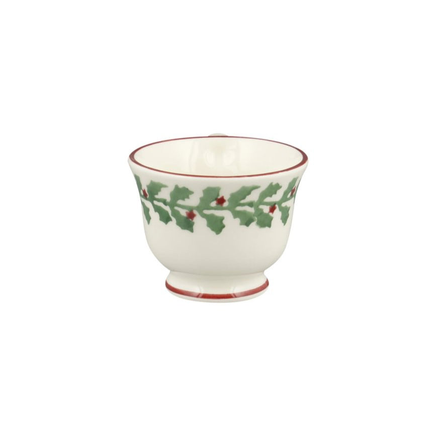 White ceramic cup with green holly design on a white background