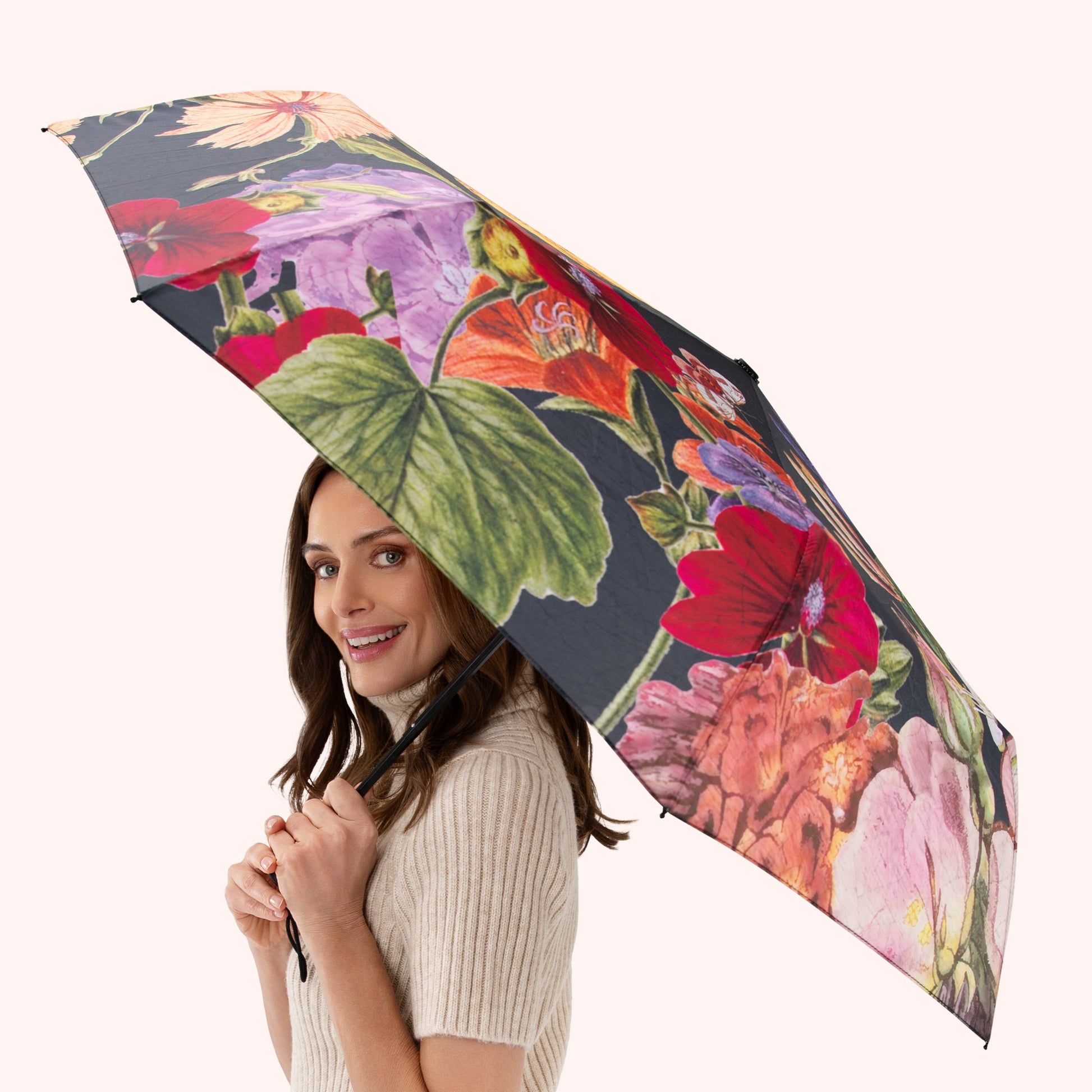 Woman holding a floral-patterned umbrella against a white background