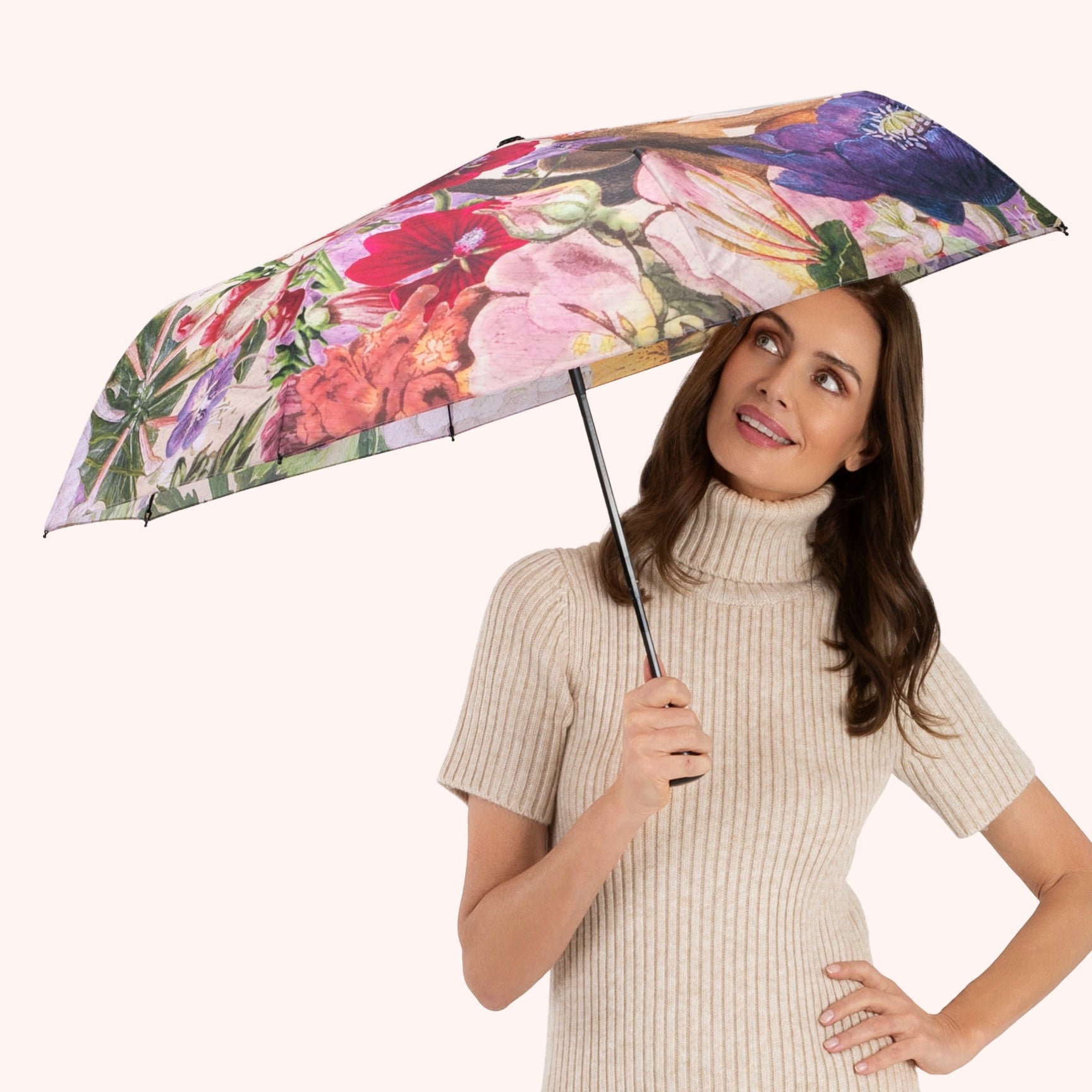 Woman holding a floral umbrella wearing a beige dress on a white background