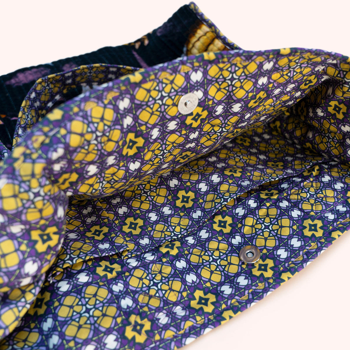 A close-up of the inside patterned fabric of a tote bag, featuring a navy blue base with yellow and white geometric and floral motifs.
