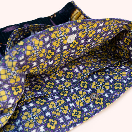 A close-up of the inside patterned fabric of a tote bag, featuring a navy blue base with yellow and white geometric and floral motifs.