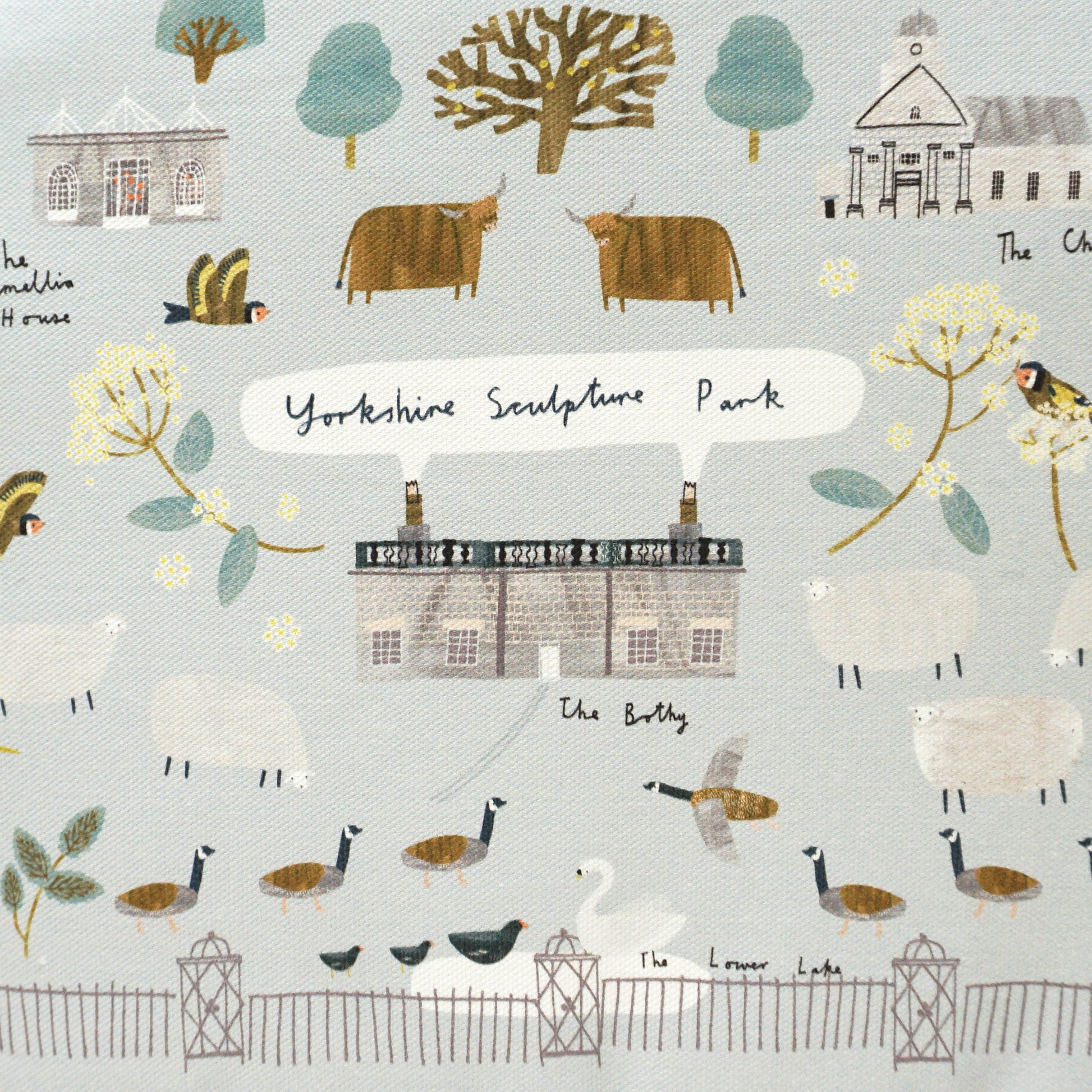 A tea cosy featuring a whimsical illustration of Yorkshire landscapes, including farms, trees, and animals like sheep and birds. The design is in soft pastel colours, with a grey trim and a tag attached, adding a charming touch to any kitchen.