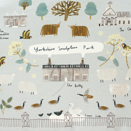 A tea cosy featuring a whimsical illustration of Yorkshire landscapes, including farms, trees, and animals like sheep and birds. The design is in soft pastel colours, with a grey trim and a tag attached, adding a charming touch to any kitchen.