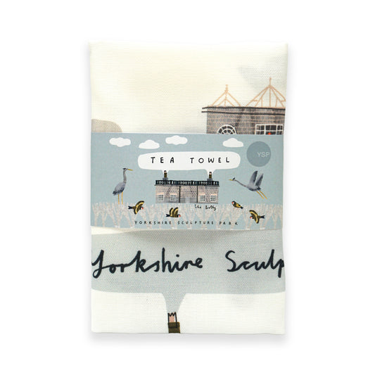 A folded tea towel featuring a design inspired by Yorkshire Sculpture Park. The towel is wrapped in a decorative band that includes the text "Tea Towel" and "Yorkshire Sculpture" alongside illustrations of birds and a building.