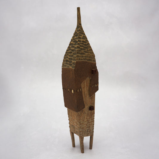 A pointy wooden house with a hand carved roof and body. The house has four legs and small wooden windows on the front.