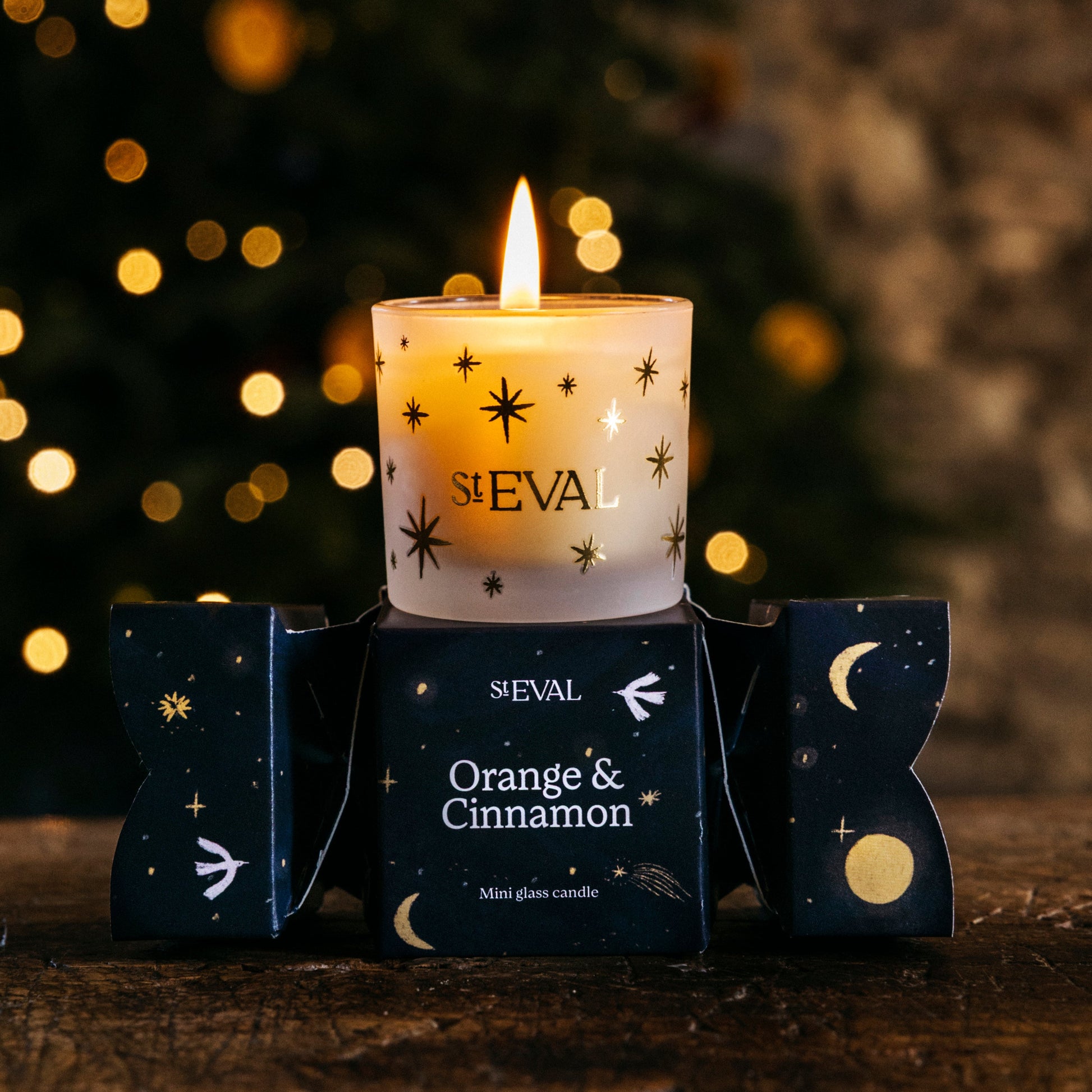 Sleval candle with 'Orange & Cinnamon' scent in front of a blurred Christmas tree.