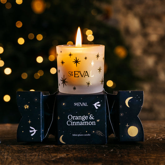 Sleval candle with 'Orange & Cinnamon' scent in front of a blurred Christmas tree.