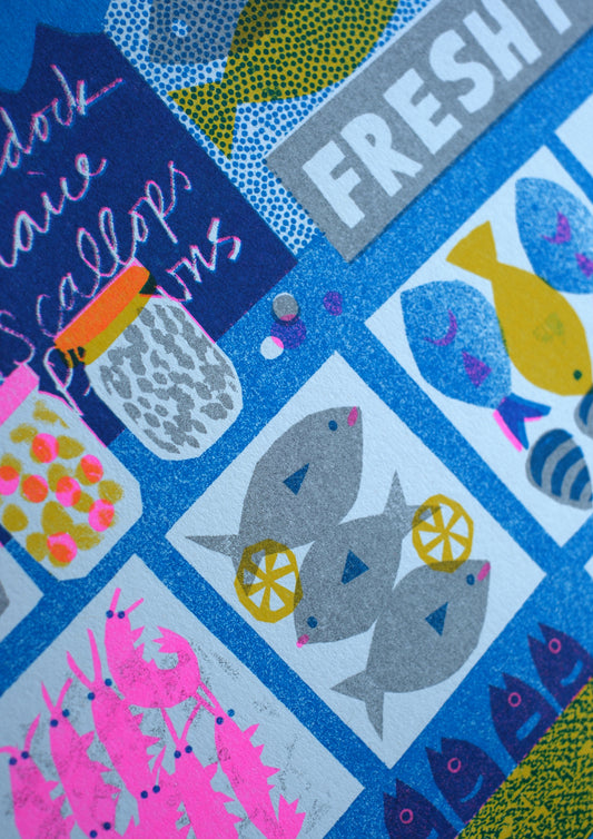 A vibrant illustration of a fish market stall featuring various seafood items. The display includes shrimp, crabs, scallops, and different types of fish, all set against a bright blue background with the words "FRESH FISH" prominently featured.