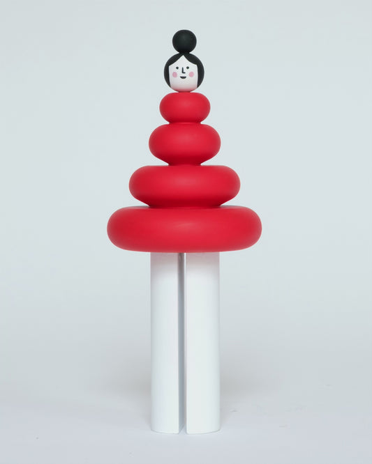 A spinning wooden figure featuring a red torso and white legs on a plain white background.